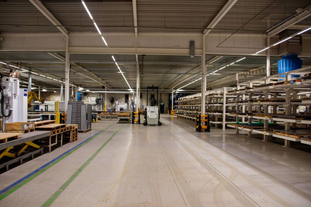 Automated ecommerce fulfillment center floor with multi-level racking, conveyor packing stations, and an autonomous mobile robot in the main aisle