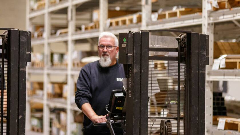 Warehouse worker scanning a product barcode with a handheld terminal at a pick station between stocked racking aisles