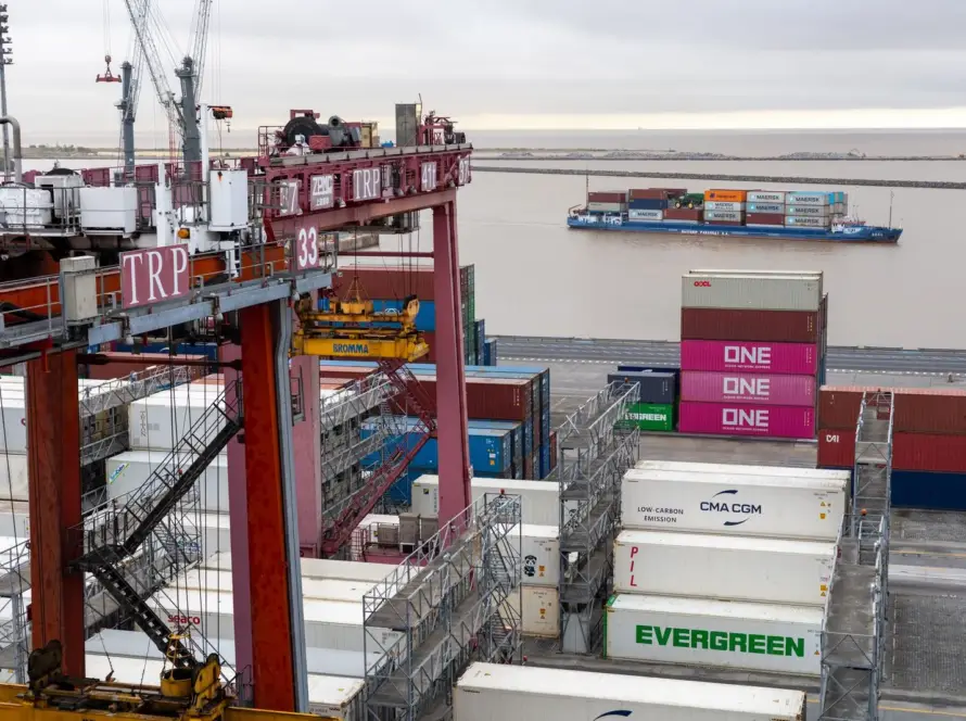 Flygfoto över Port Newark-Elizabeth Marine Terminal i New Jersey med röda ship-to-shore-kranar som lastar fraktcontainrar på ett Maersk-containerfartyg vid kajen, vilket visar den största containerhamnen på östkusten som stöder dropshipping-import från Asien.